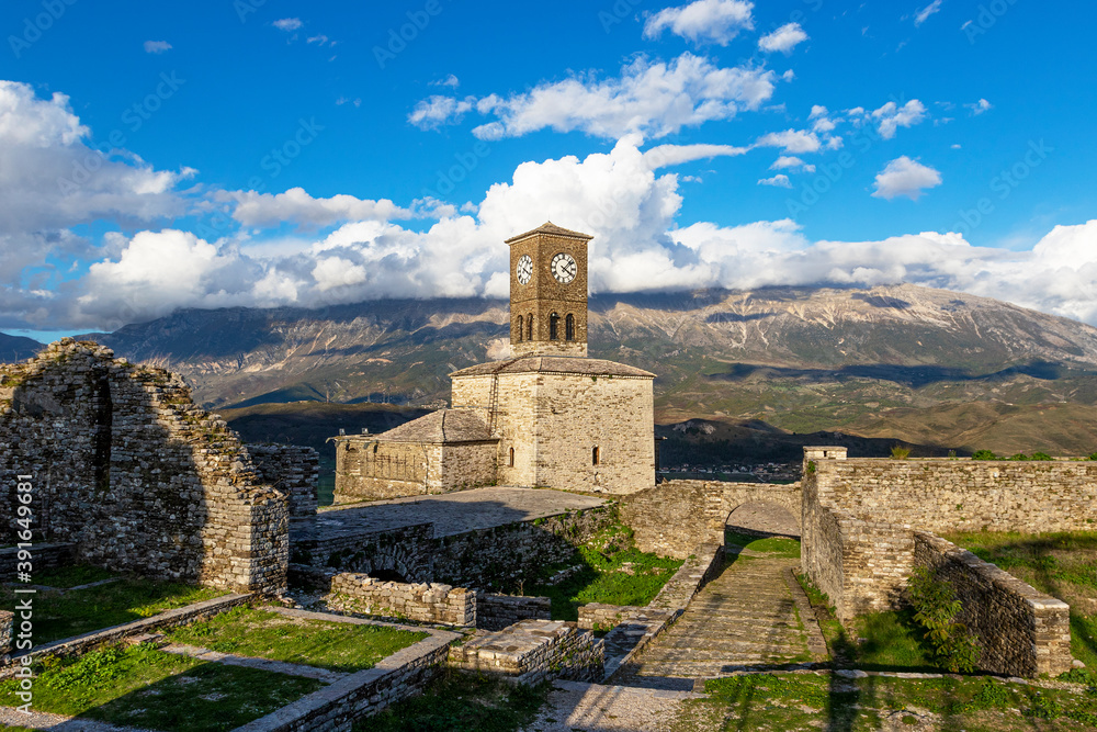 Scenic view of clock tower in castle of Gjirokastra with mountains and clouds - obrazy, fototapety, plakaty 