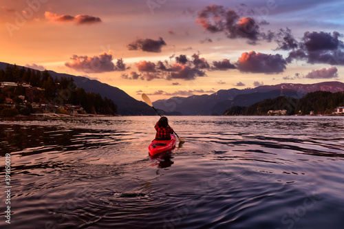 Adventurous Girl Paddling on a Bright Red Kayak in calm ocean water. Dramatic Colorful Sunset Sky. Taken in Indian Arm, Deep Cove, North Vancouver, British Columbia, Canada. © edb3_16