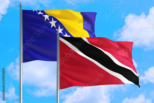 Trinidad And Tobago and Bosnia Herzegovina national flag waving in the windy deep blue sky. Diplomacy and international relations concept.