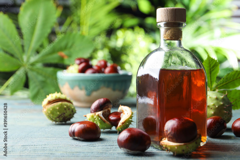 Chestnuts and bottle of essential oil on table against blurred background. Space for text Chestnuts and bottle of essential oil on table against blurred background. Space for text
