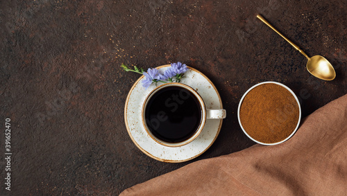 Composition of chicory drink, chicory powder, napkins and spoon on a brown background. Healthy chicory beverage. Copy space, top view, flat lay.