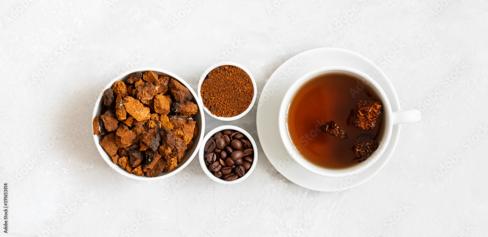Chaga mushroom drink with coffee and chopped chaga pieces on a white background. New superfood trend. Top view, flat lay. Chaga mushroom drink with coffee and chopped chaga pieces on a white background. New superfood trend. Top view, flat lay.