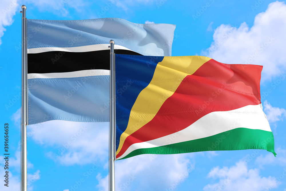 Seychelles and Botswana national flag waving in the windy deep blue sky. Diplomacy and international relations concept. Seychelles and Botswana national flag waving in the windy deep blue sky. Diplomacy and international relations concept.