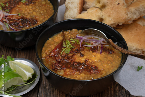 Vegan split green pea soup with tempered spices, flat breads on wooden table, copy space