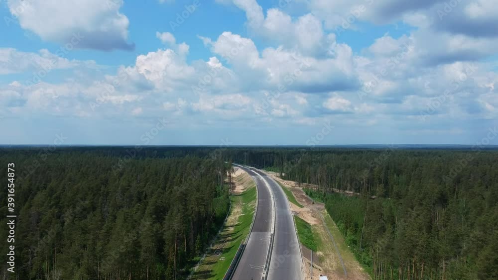 Construction of a high speed highway in the forest. Aerial video shooting from drone. Green trees. New asphalt pavement of the road. High quality FullHD footage Construction of a high speed highway in the forest. Aerial video shooting from drone. Green trees. New asphalt pavement of the road. High quality FullHD footage