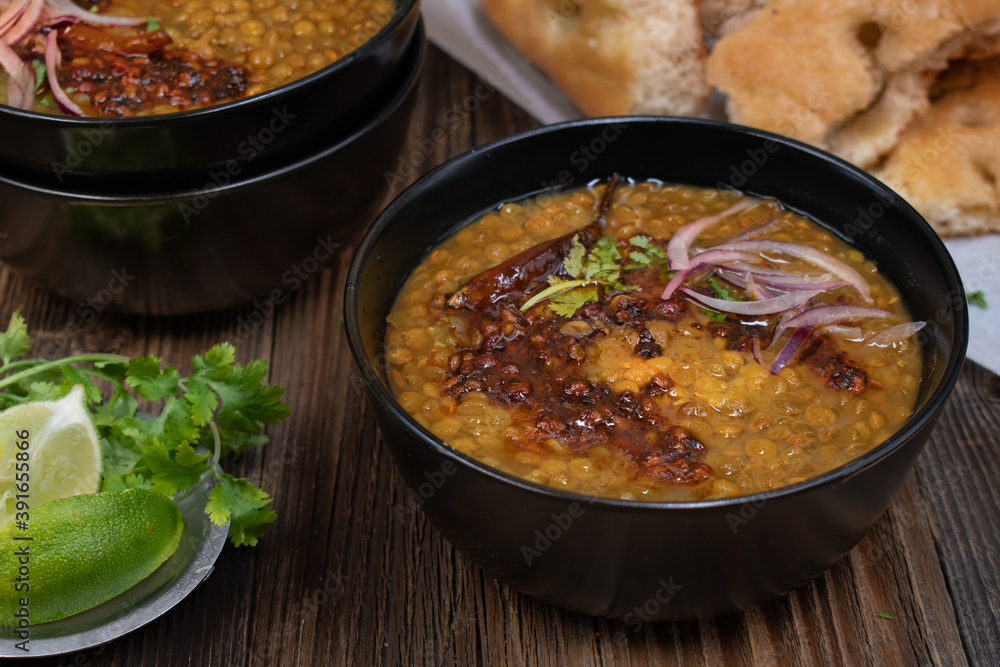 Vegan split green pea soup with tempered spices, flat breads on wooden table, copy space