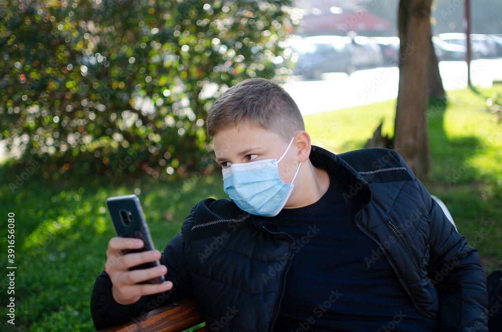 People with face mask. Concept with copy space. Portrait of young man at the street. Photo outdoors in a city. Back to school. School-age boy with a protective medical mask on her on his face. People with face mask. Concept with copy space. Portrait of young man at the street. Photo outdoors in a city. Back to school. School-age boy with a protective medical mask on her on his face.
