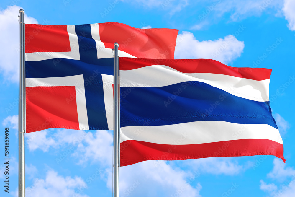 Thailand and Bouvet Islands national flag waving in the windy deep blue sky. Diplomacy and international relations concept. Thailand and Bouvet Islands national flag waving in the windy deep blue sky. Diplomacy and international relations concept.