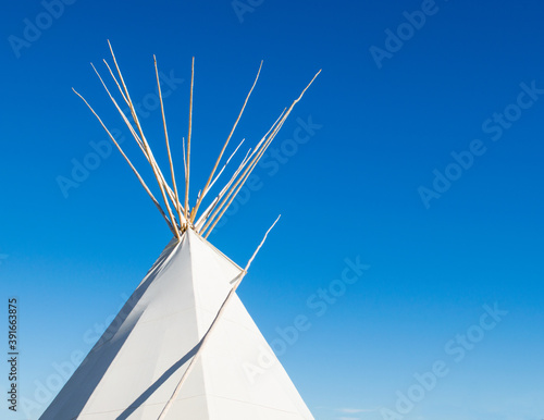 a Native American tipi under bright blue skies with copy space