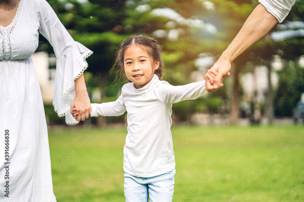 Portrait of enjoy happy love asian family father and mother holding little asian daughter girl hand in moments good time in summer park at home