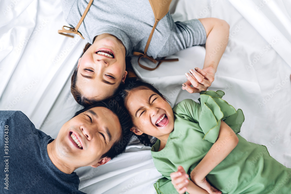 op view of portrait enjoy happy smiling love asian family father and mother with young parents little asian daughter girl looking at camera in moments good time lying on the floor at home