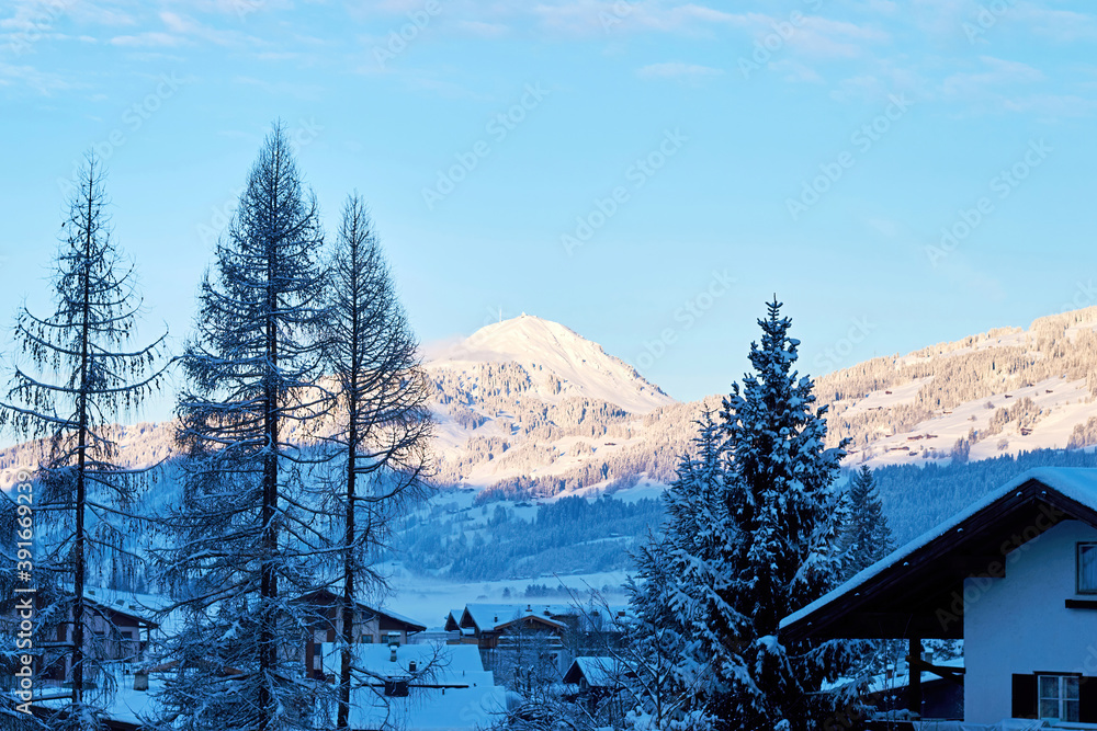 Fototapeta premium Old Austrian village on the snowy slope in the shadow of the mountains. Ski and leisure activity travel destinations