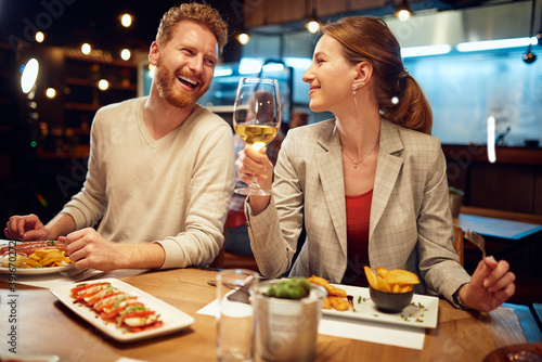 Cuadro en lienzo Smiling cheerful couple sitting in a restaurant, having dinner and chatting