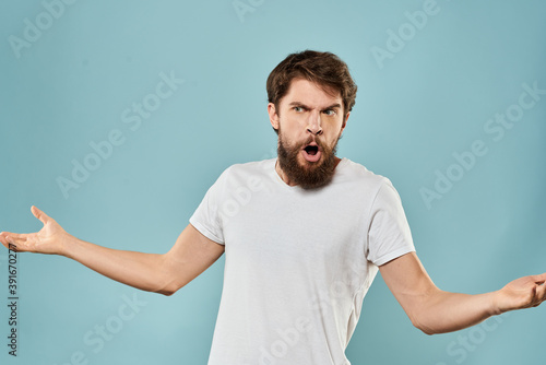 Man gestures with his hands emotions displeasure white t-shirt blue background