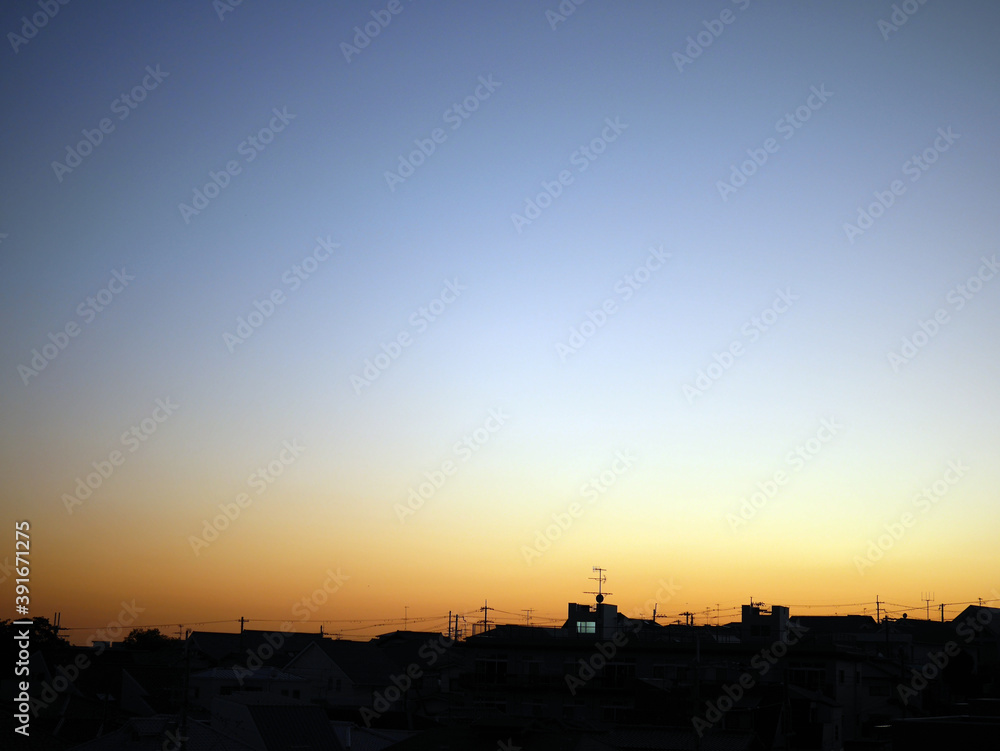 Gradient sunset sky with the silhouettes of houses in Japan.