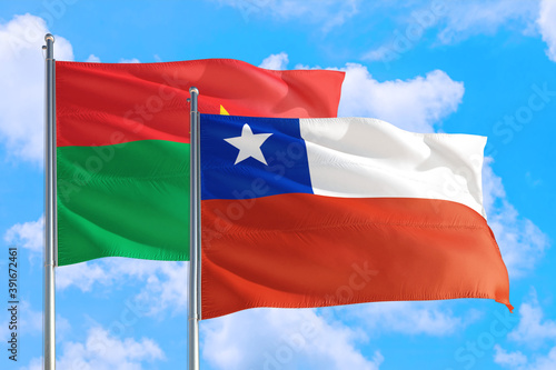 Chile and Burkina Faso national flag waving in the windy deep blue sky. Diplomacy and international relations concept.