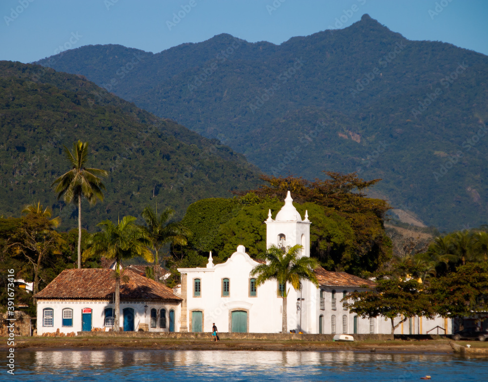 Church of Nossa Senhora das Dores, built in the year 1800 by the sea. In the background the mountains covered with Atlantic forest. Paraty, State of Rio de Janeiro, Brazil.