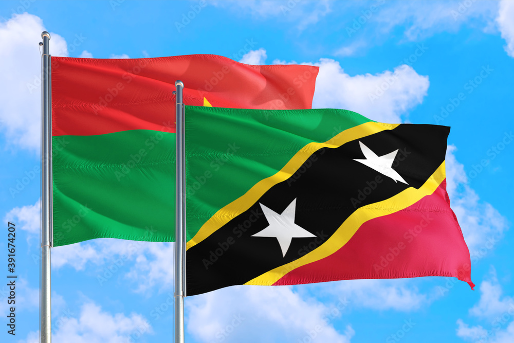 Saint Kitts And Nevis and Burkina Faso national flag waving in the windy deep blue sky. Diplomacy and international relations concept. Saint Kitts And Nevis and Burkina Faso national flag waving in the windy deep blue sky. Diplomacy and international relations concept.