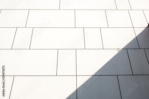 abstract background. Minimalist Detail Of White Paneled Contemporary Building Wall, With Bright Sunlight And Hard Shadow, Backgrounds, Textures. Stock Photograph.