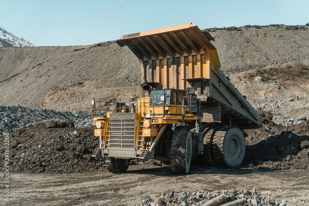 Obraz premium The mining dump truck unloads ore at the gold mining site.