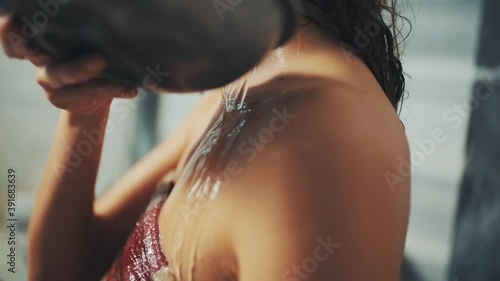 woman in loincloth pours water bowl over her shoulder in Turkish bath. close up.