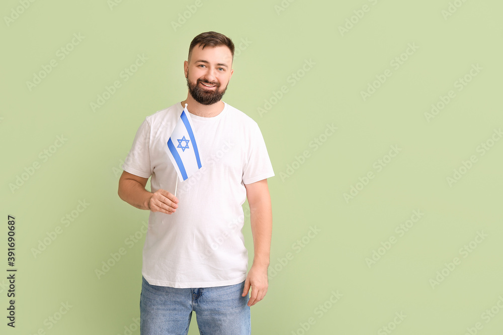 Fototapeta premium Man with the flag of Israel on color background