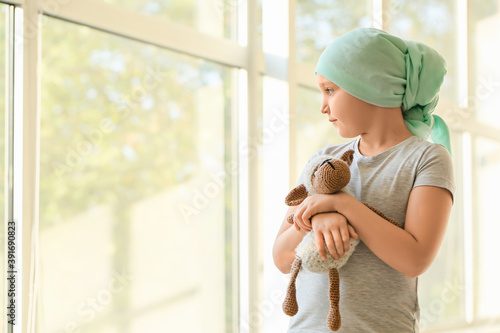 Obraz na plátně Little girl after course of chemotherapy near window in clinic