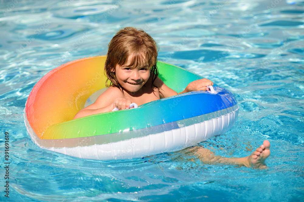Healthy kids lifestyle. Cute funny little toddler boy in a colorful swimming suit and sunglasses relaxing with toy ring floating in a pool having fun during summer vacation in a tropical resort.