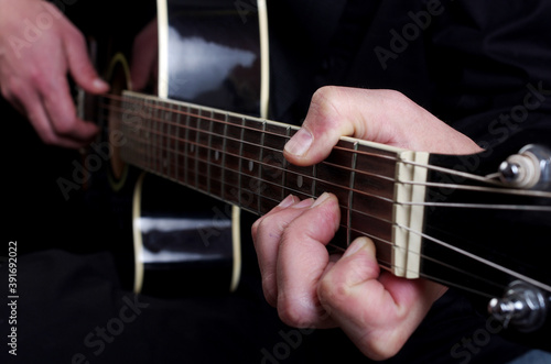 The guitarist plays a black acoustic guitar.