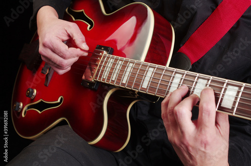 The guitarist plays a red jazz electric guitar.Close up.