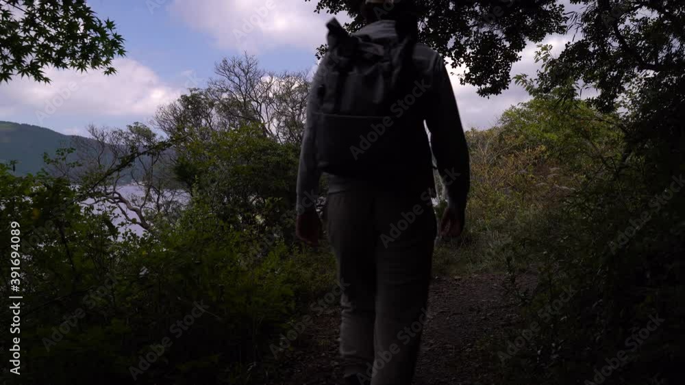 Male hiker walking through green forest next to beautiful lake and blue sky Male hiker walking through green forest next to beautiful lake and blue sky