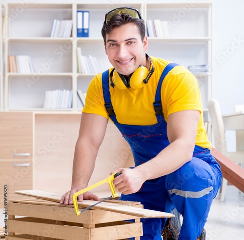 Repairman carpenter working sawing a wooden board with a hand sa