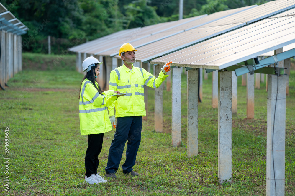Technician working with engineer planning new ecology project around field of solar panels. Technician working with engineer planning new ecology project around field of solar panels.