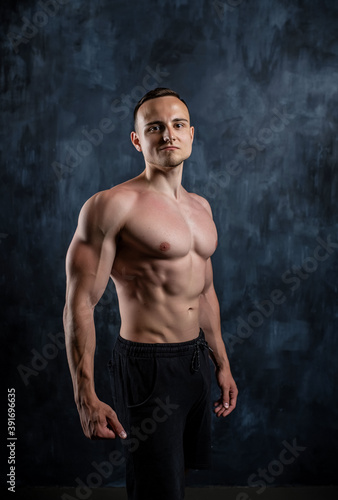 Handsome athletic man posing on black background. © Sergei