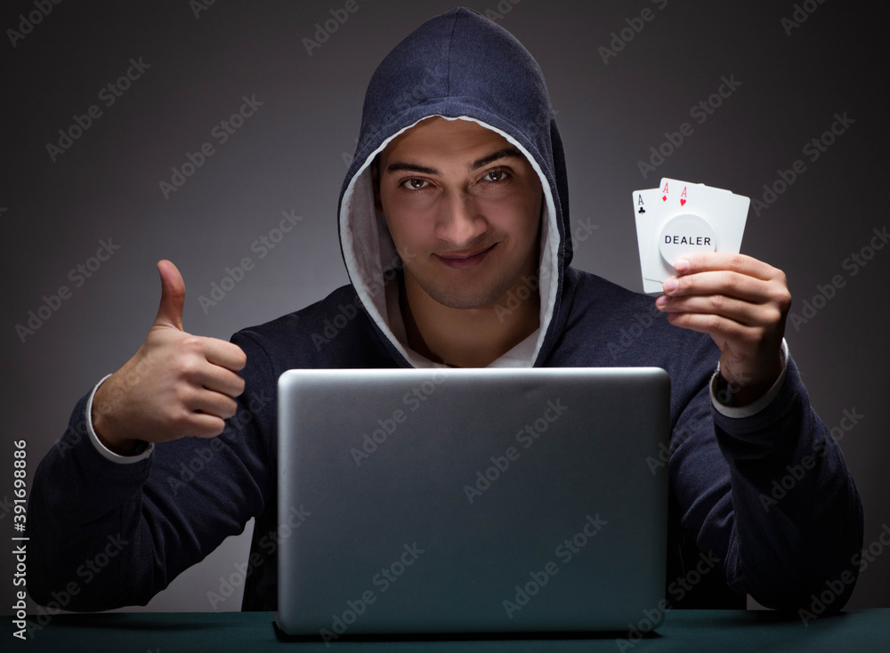 Young man wearing a hoodie sitting in front of a laptop computer Young man wearing a hoodie sitting in front of a laptop computer