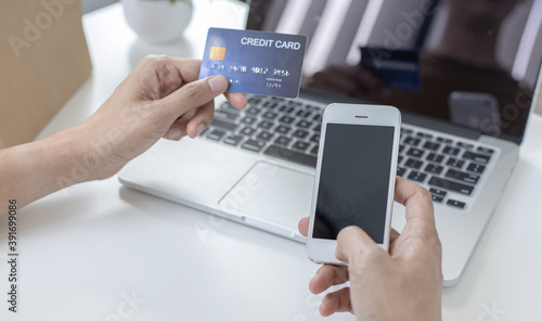 Young man with a credit card shopping online on a laptop.