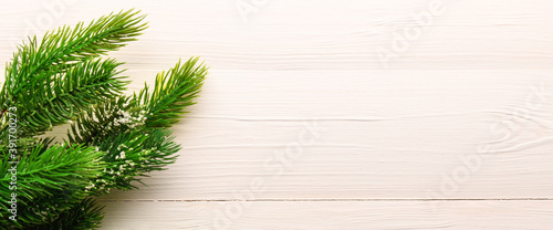 Christmas tree branches on a light wooden background. New year and Christmas background. Space for text. Banner.