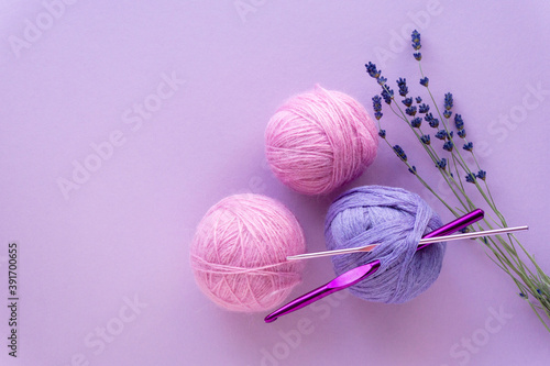 Flat lay of colored yarn balls for crocheting with lavender on a lilac background, top view
