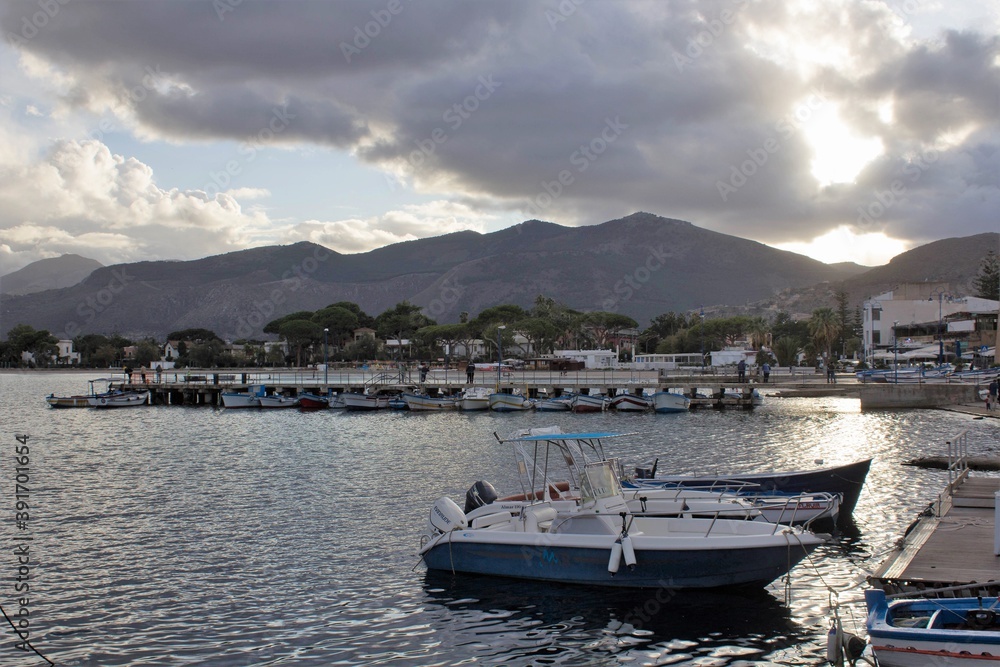 evocative image of fishing boats moored in the harbor with the coastline in the background and bad weather in the evening
