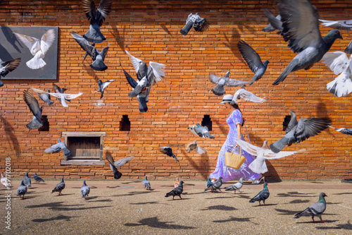 Asian woman tourist walks through the middle of a pigeon next to Tha Phae Gate in Chiang Mai, Thailand.