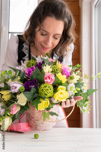 A woman collects a decorative bouquet of paper flowers.