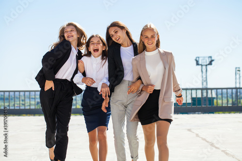 Four happy girlfriends in school uniform