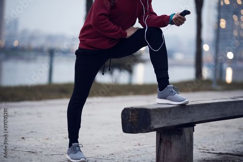 Athletic sporty man training in hoodie sweatshirt in urban city park.