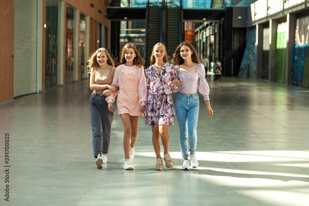 Four happy girlfriends are walking in the mall