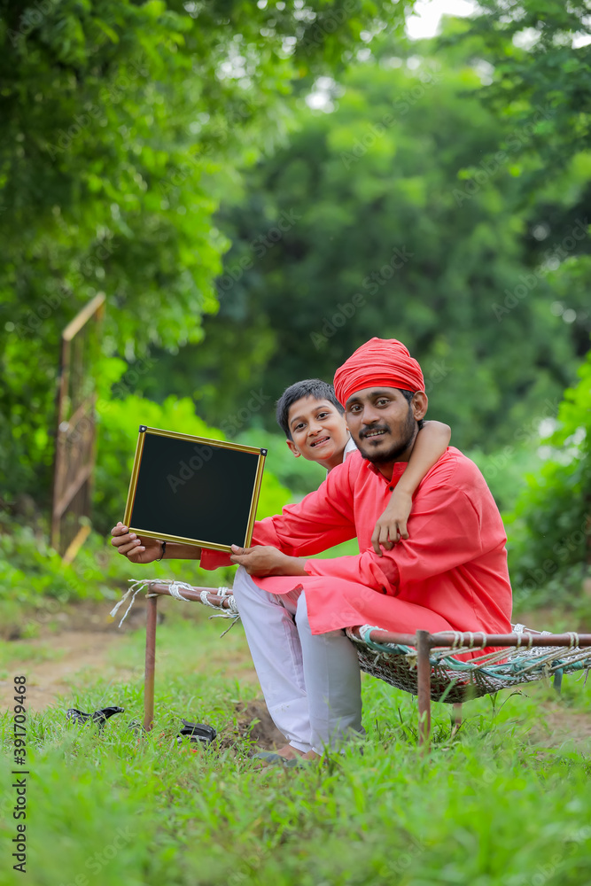 young indian farmer showing blank chalkboard with his child young indian farmer showing blank chalkboard with his child