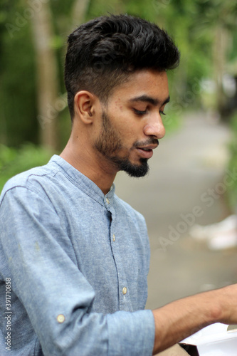 close portrait of young bearded man in cap loving and touching trees in amazing nature forest