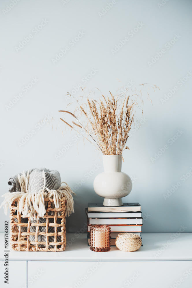 cozy modern interior details with fluffy reeds, candles and books in beige tones. Minimalist nordic design home.