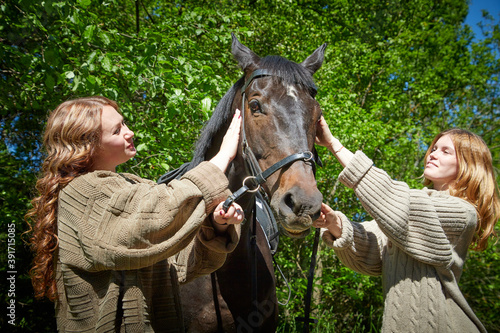 Two girls with big horse in a summer day