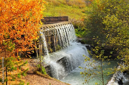 Fototapeta Naklejka Na Ścianę i Meble -  Waterworks for draining water from the lake surrounded by autumn trees