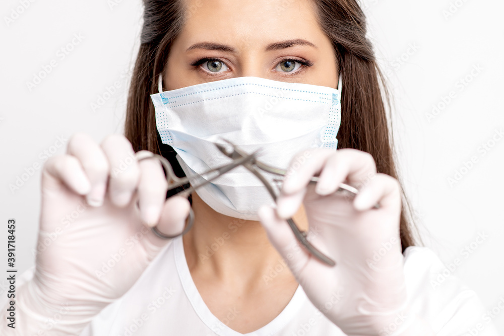 Portrait of manicure master with white protective mask holding manicure tools on white background